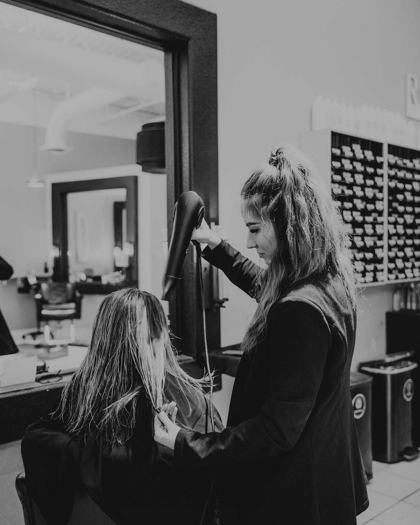 Hairdresser blow-drying woman's hair in salon.